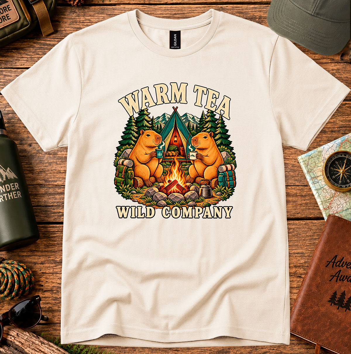 Warm Tea Wild Company T-shirt showing two capybaras with mugs beside a campfire, tent and pine trees