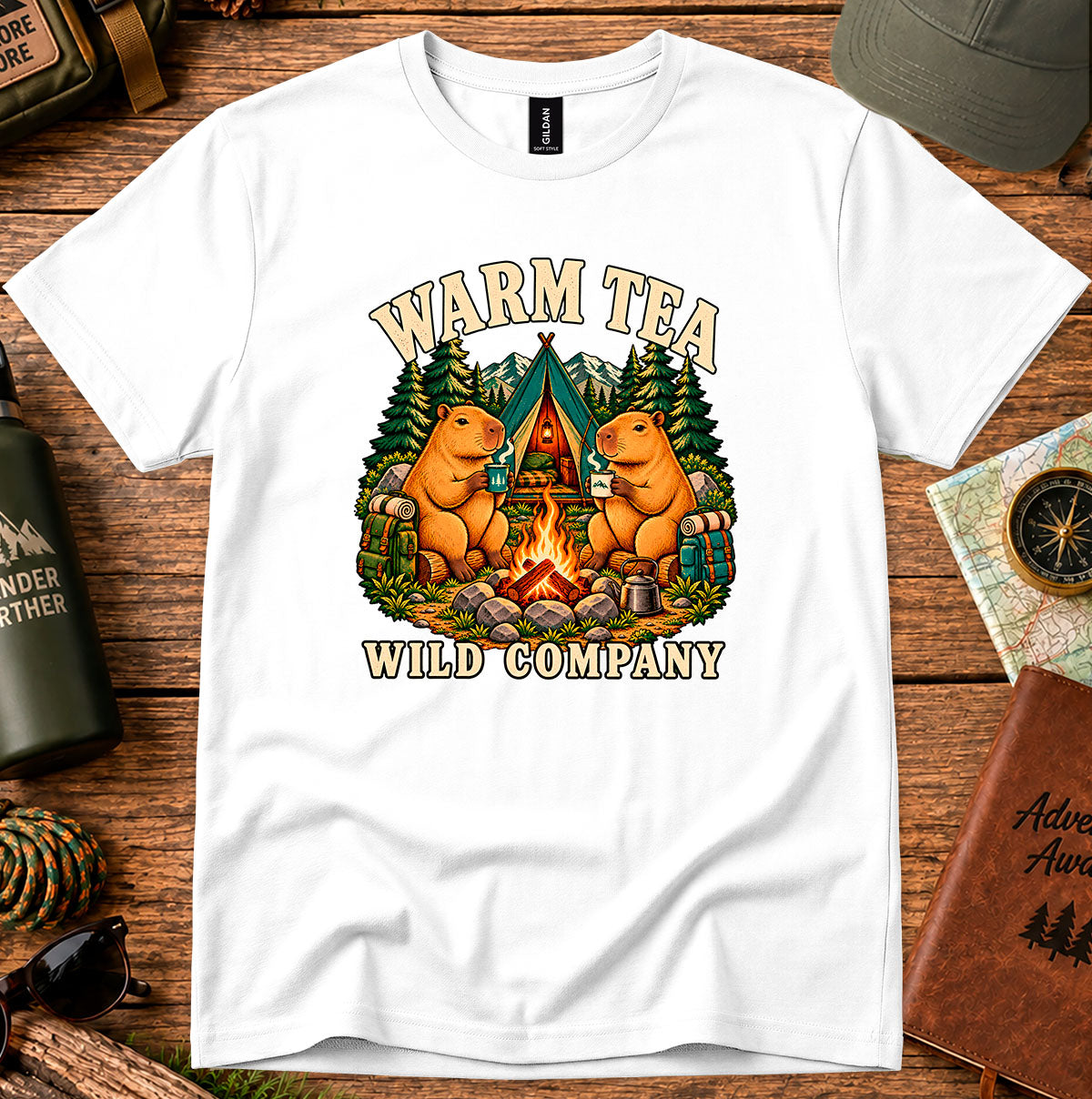 Warm Tea Wild Company T-shirt showing two capybaras with mugs beside a campfire, tent and pine trees