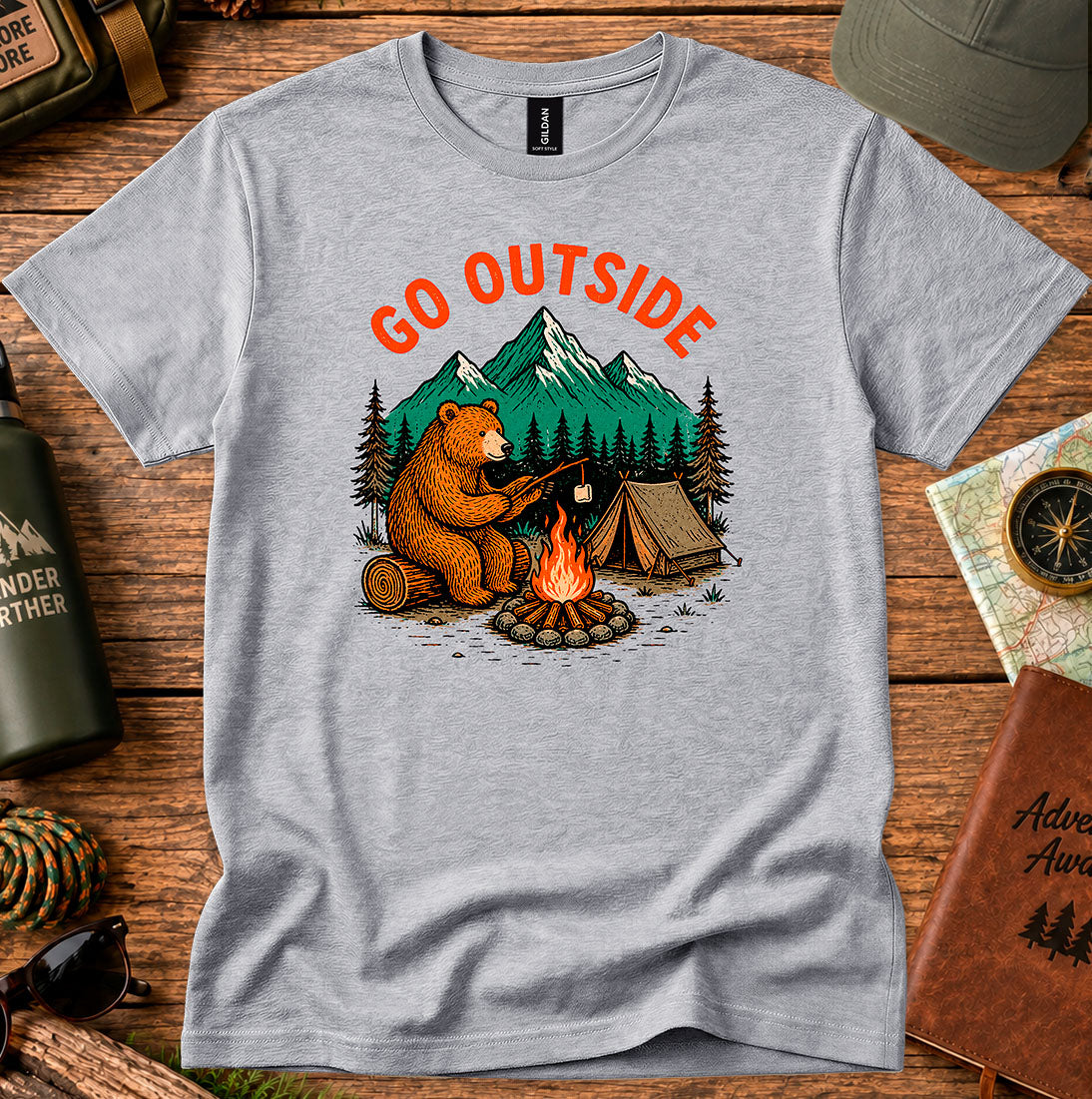 T-shirt featuring a bear warming its paws by a campfire with Go Outside lettering