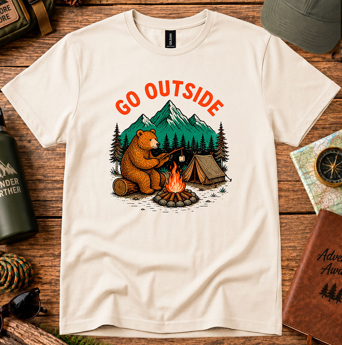 T-shirt featuring a bear warming its paws by a campfire with Go Outside lettering