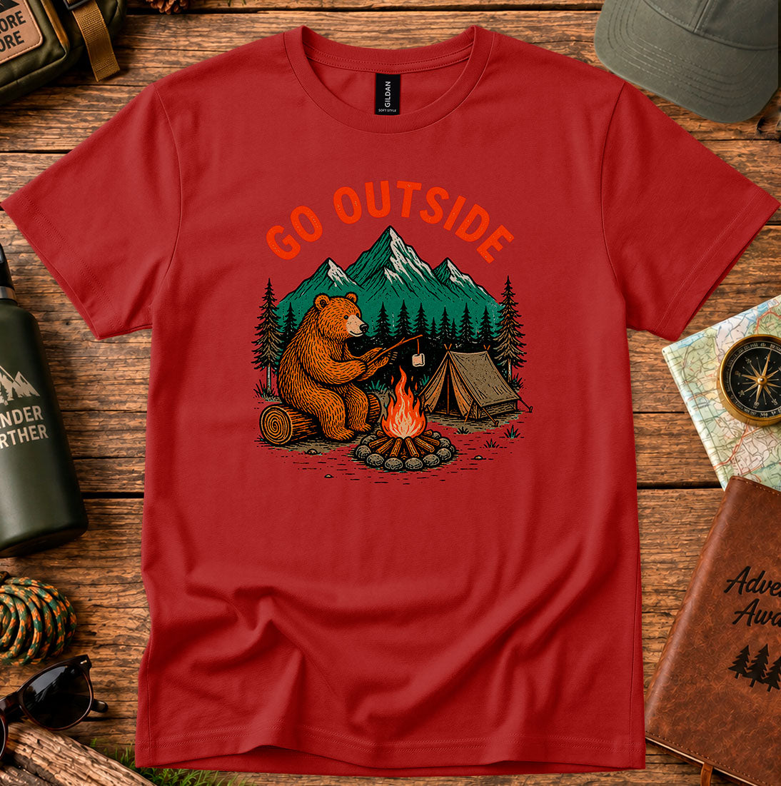 T-shirt featuring a bear warming its paws by a campfire with Go Outside lettering