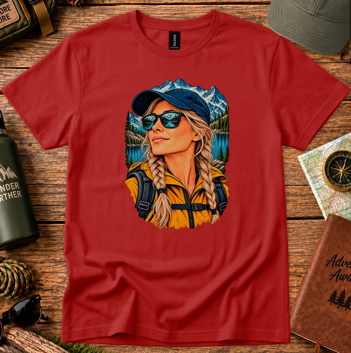 Red T-shirt featuring a woman wearing a blue cap and sunglasses with mountain and lake scenery