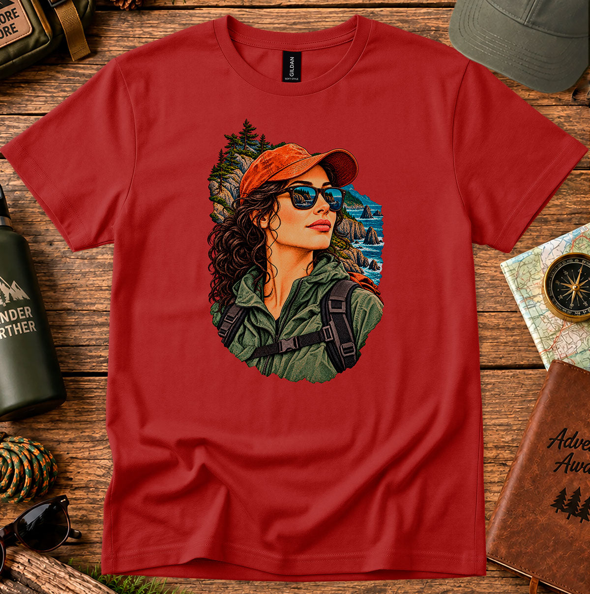 Red T-shirt featuring a woman in a red cap and sunglasses surrounded by mountain and forest scenery