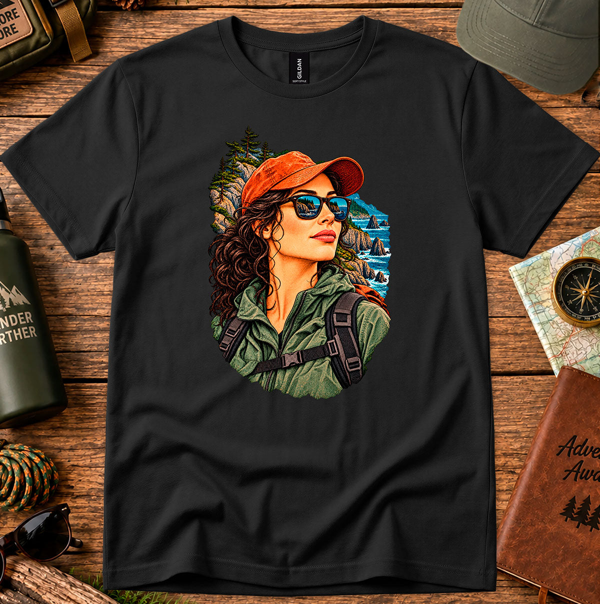Black T-shirt featuring a woman in a red cap and sunglasses surrounded by mountain and forest scenery