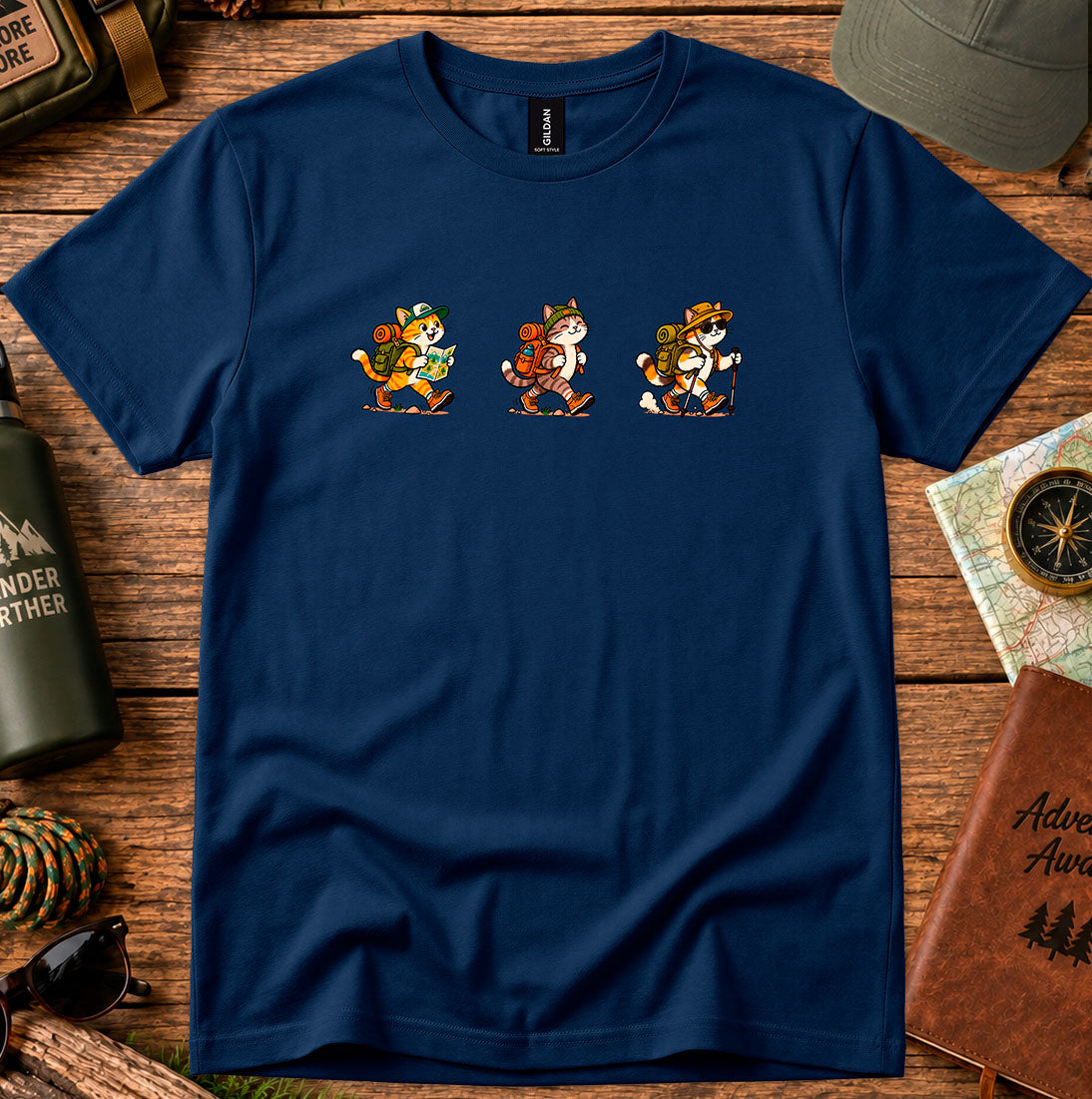 T-shirt featuring three cartoon cats carrying backpacks and hiking gear