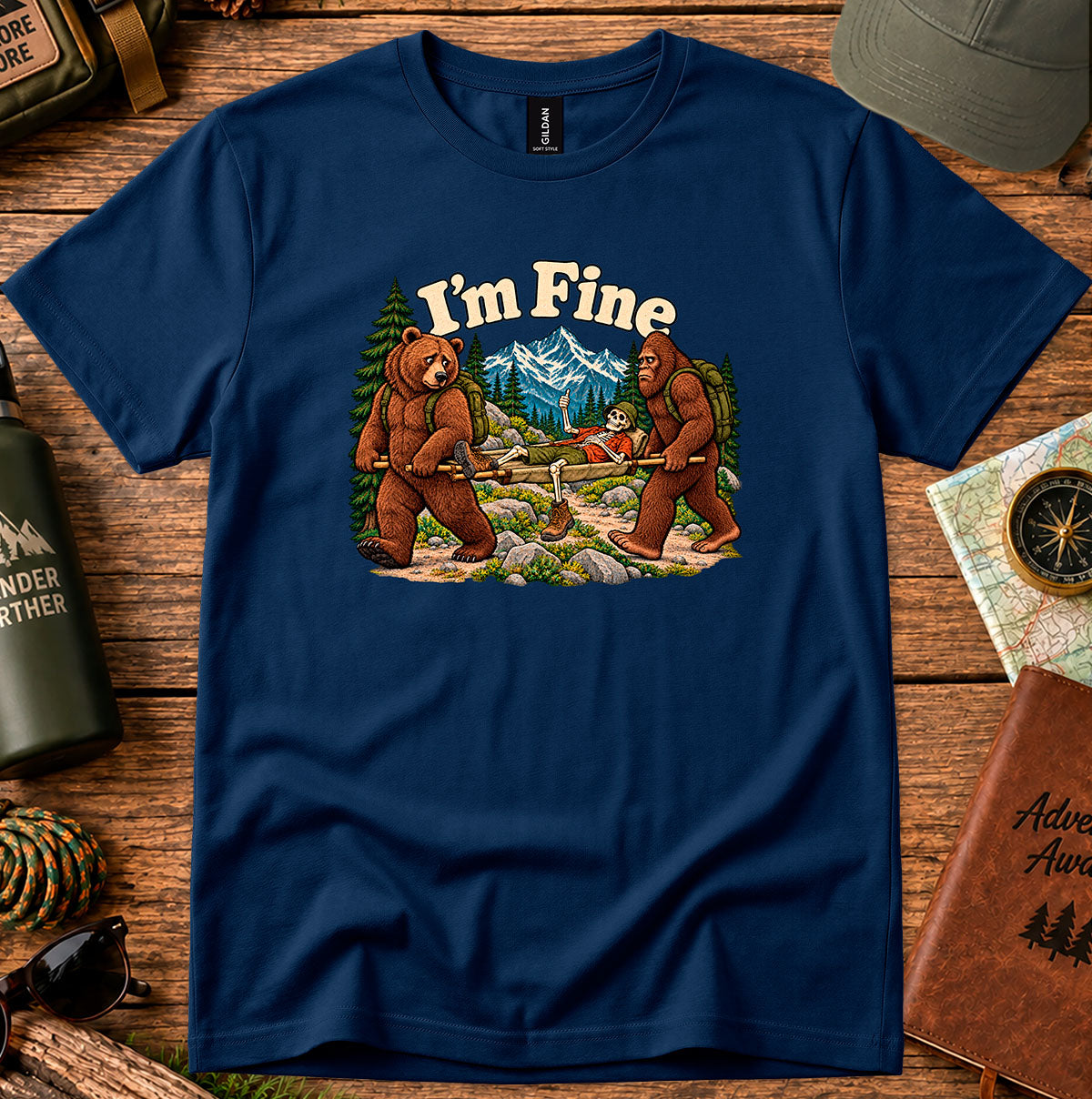 I'm Fine hiking T-shirt with a bear and bigfoot carrying a skeleton on a stretcher among mountains and pine trees