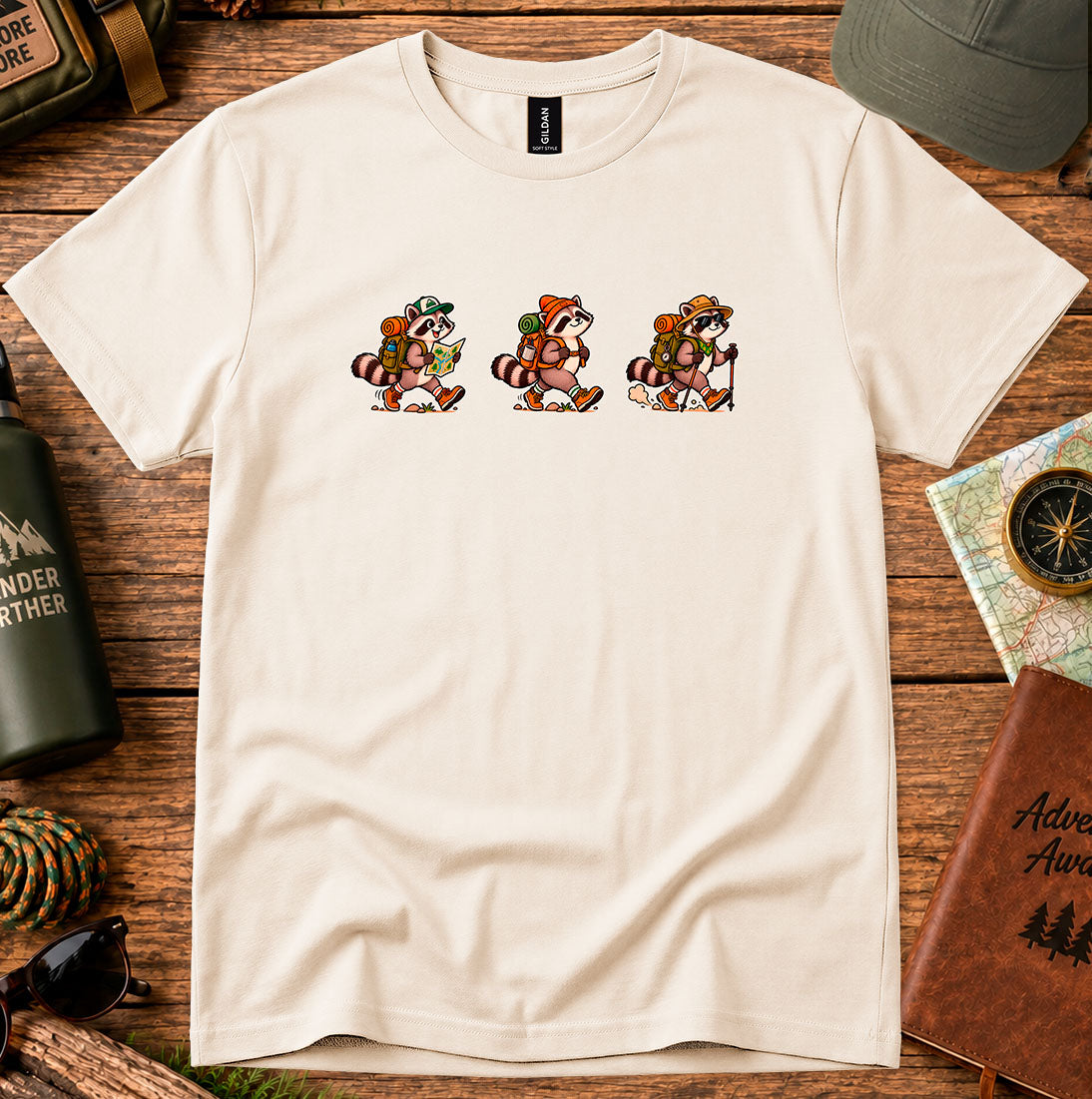 T-shirt featuring three vintage-style raccoons walking with hiking gear