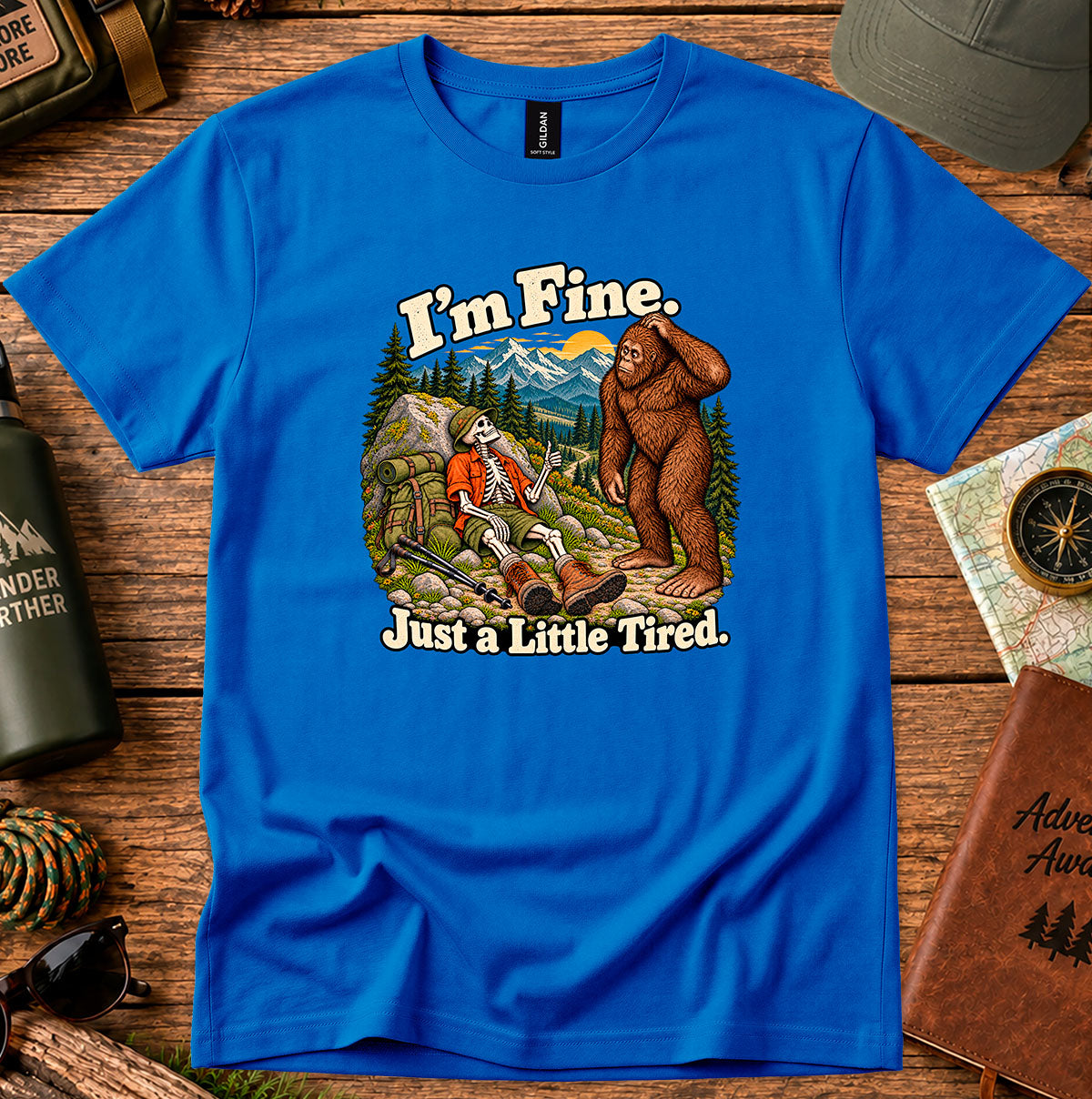 I'm Fine Just a Little Tired T-shirt with a resting skeleton hiker and bigfoot on a mountain trail
