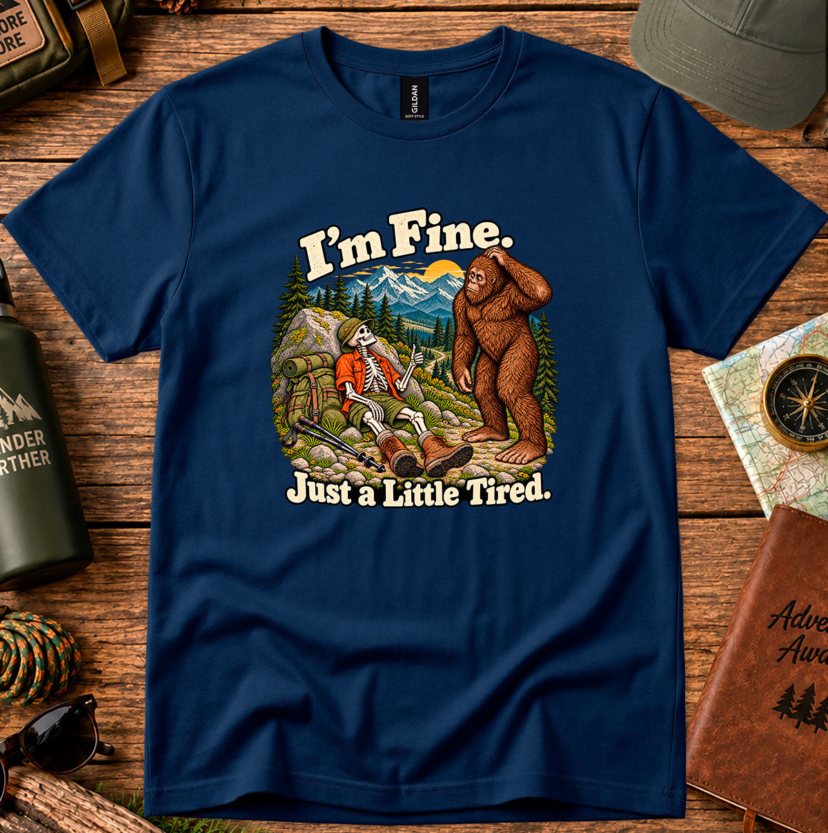 I'm Fine Just a Little Tired T-shirt with a resting skeleton hiker and bigfoot on a mountain trail