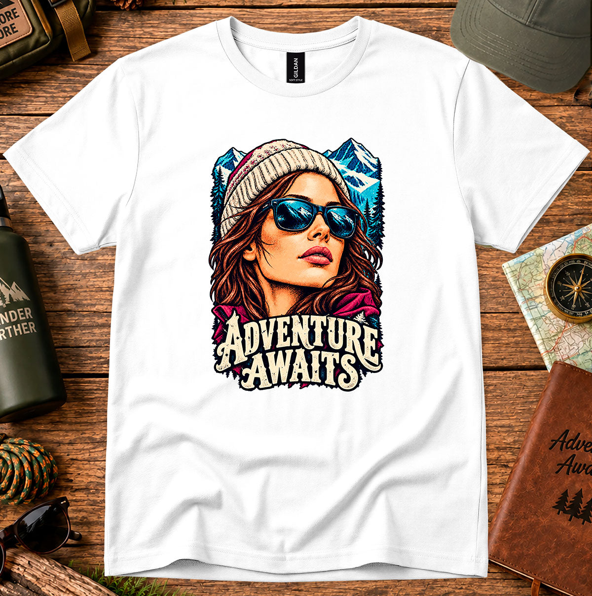 Adventure Awaits T-shirt showing an explorer in sunglasses framed by mountain peaks