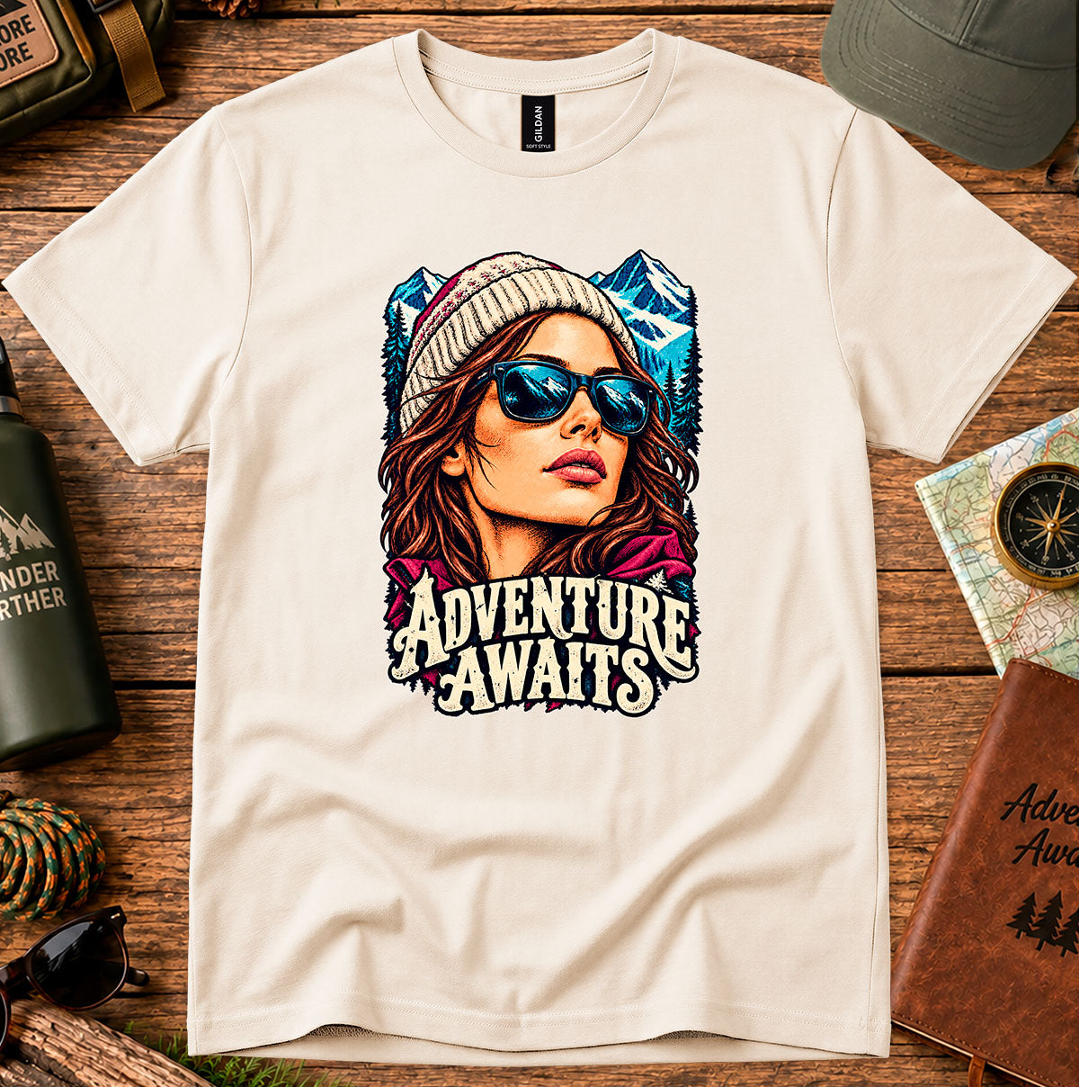 Adventure Awaits T-shirt showing an explorer in sunglasses framed by mountain peaks