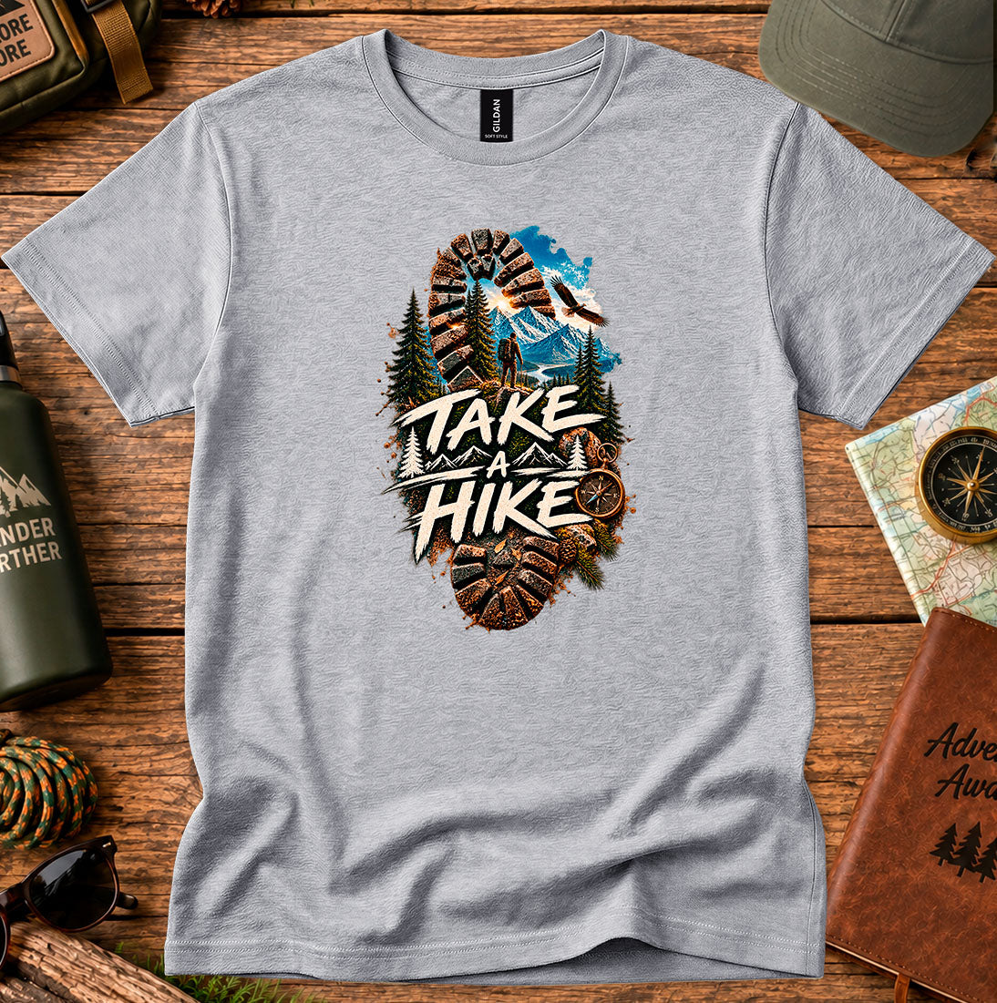 T-shirt featuring a bootprint framing a hiker, pine trees and mountain peaks