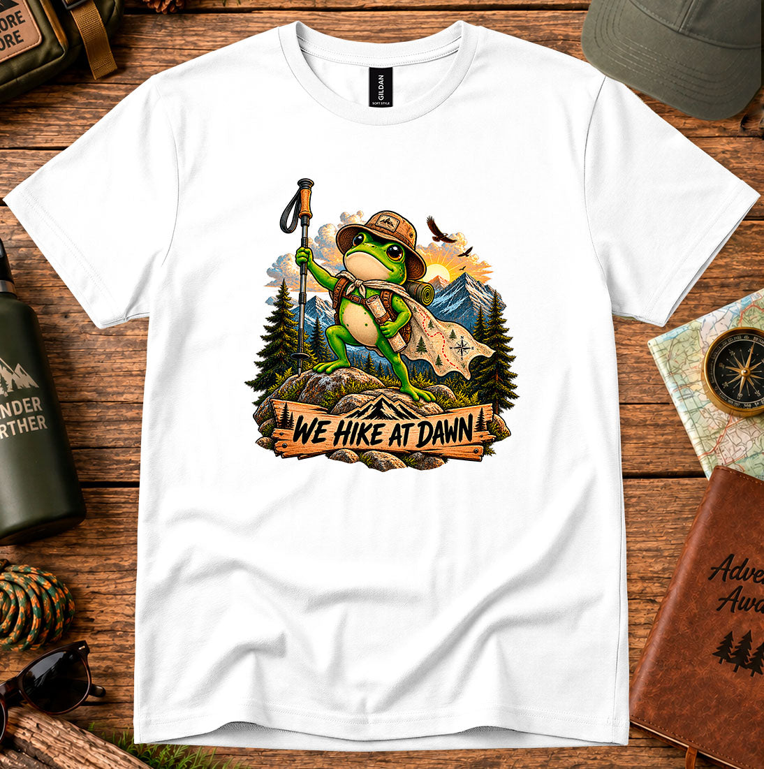 T-shirt featuring a backpack-wearing frog on a rock with mountains and pine trees